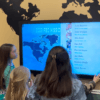 kids interacting with a touchscreen missions wall board image