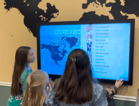 kids interacting with a touchscreen missions wall board image
